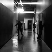 Black-and-white image of dark corridor with three people in it